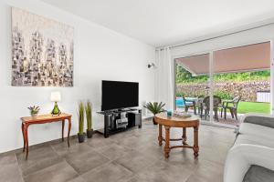 a living room with a tv and a couch at Villa les Coteaux du soleil in Carcès