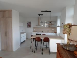 a kitchen with white cabinets and a table and stools at Gîte des Bruyeres in Beynat