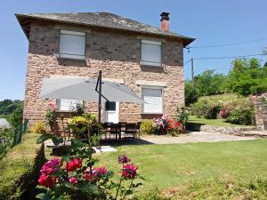 a stone house with a table and an umbrella at Gîte des Bruyeres in Beynat