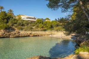 a beach with people walking on the sand and water at Villa Sa Caleta de Cala D'or in Santanyi
