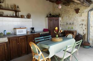 a kitchen with a table with chairs and a microwave at Chambres D'hôtes La Buissonnière in Théziers