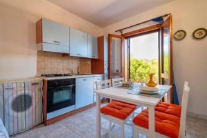 a kitchen with a white table and chairs and a window at Casetta paradiso in Costa Paradiso