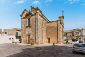 an old brick building with cars parked in a parking lot at Corte Cochlea Lu Sciardinu Suite in Cannole