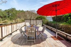 a table with a red umbrella on a deck at La chambre L'ile de Tom in Lège-Cap-Ferret +6 photos
