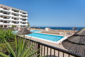a view of a swimming pool with a building and the ocean at Casa Relax Marine in Costa Del Silencio