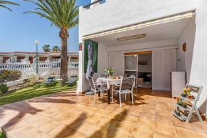a patio with a table and chairs and palm trees at Casa Relax Marine in Costa Del Silencio