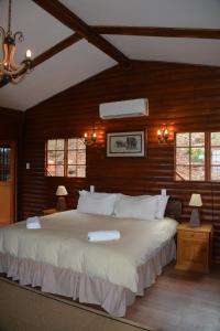 a bedroom with a large white bed with wooden walls at Amafu Forest Lodge in Hoedspruit