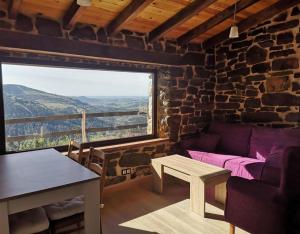 a living room with a purple couch and a large window at Casa Rural El Picón in Entrambasaguas