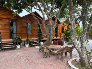 a house with a table and benches next to a tree at Cô Tô Homestay 368 in Chung Cap