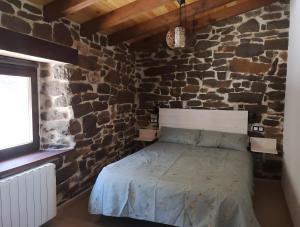 a bedroom with a stone wall with a bed at Casa Rural El Picón in Entrambasaguas