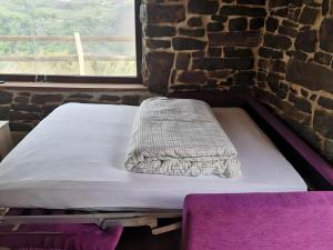 a bed in a room with a stone wall at Casa Rural El Picón in Entrambasaguas +3 photos