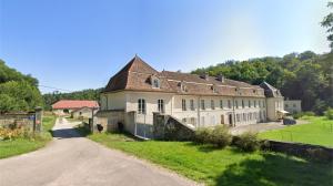 an old building on a field with a road at Gîte de l'Abbaye chambre triple in Rollainville