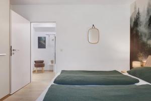 a white bedroom with a bed and a chair at Schwarzwald-Kitz mit Pool und Sauna in Lenzkirch +24 photos