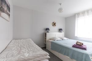 a white bedroom with two beds and a window at Entre plage, forêt et villages in Mimizan