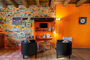 an orange room with a stone wall with a table and chairs at Nogueira in Vega de Logares