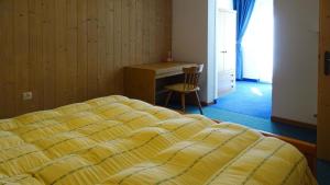 a bedroom with a bed and a desk and a chair at La Capinera Canazei Apartments in Canazei