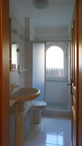 a bathroom with a sink and a toilet and a window at La Capinera Canazei Apartments in Canazei +17 photos
