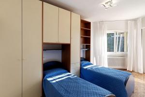 two beds in a bedroom with blue sheets at Casa Alizia in Ospedaletti