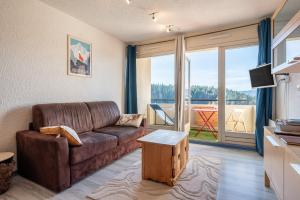 a living room with a couch and a large window at Métamorphose Au Sommet in Villard-de-Lans