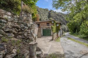 a stone building with a green garage next to a road at Cal Manyà in Susqueda