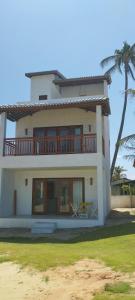 a large white house with a balcony and a table at Casa Amarela - Guajiru in Trairi +3 photos