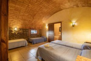 a room with two beds and a stone wall at Volta De Ferreres in Olvan