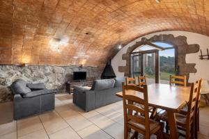 a living room with a table and chairs and a stone wall at Volta De Ferreres in Olvan