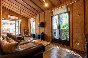 a living room with a leather couch and a large window at Chalet Bangli in Lacanau