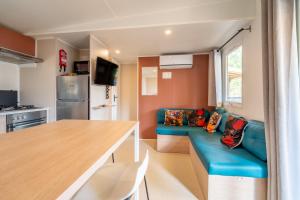 a living room with a blue couch and a kitchen at Mobilhome au Camping La Yole in Vendres