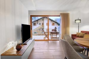 a living room with a flat screen tv and a table at Rostrini Family Home Retreat in Cavalese