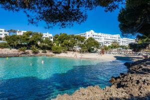 a beach with people in the water and buildings at Beach Apartment 11 in Cala d´Or