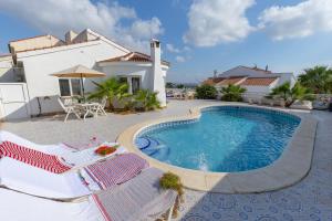 a swimming pool with two deck chairs and a house at Fidalsa Golf Beach in Ciudad Quesada