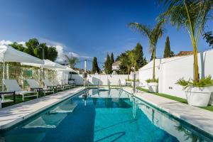 Costa del Sol Torremolinos Hotel في توريمولينوس: وجود مسبح مع الكراسي والنخيل بجانب مبنى