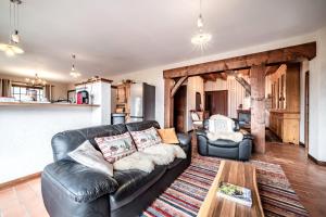 a living room with a leather couch and a table at Séjour dans ferme de 1876 in Marignier