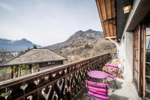 a balcony with pink chairs and a table and a mountain at Séjour dans ferme de 1876 in Marignier