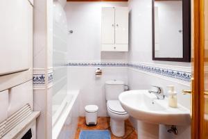 a white bathroom with a toilet and a sink at Torre Playa in Torre del Mar +14 photos