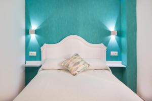a bedroom with a white bed with blue walls at Torre Playa in Torre del Mar