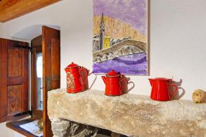 three red vases sitting on top of a fireplace at Maison Core' in Fontainamore