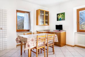a kitchen with a table and chairs and a television at Appartamenti l'Edera in Cavedago