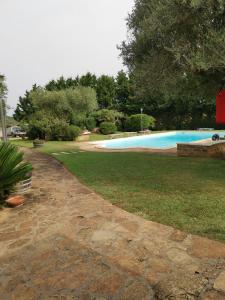 a swimming pool in a yard next to a grass field at Casa Pito Pito in Alghero