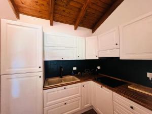 a kitchen with white cabinets and a sink at Villa Sole con piscina privata in Cuile Pazzoni