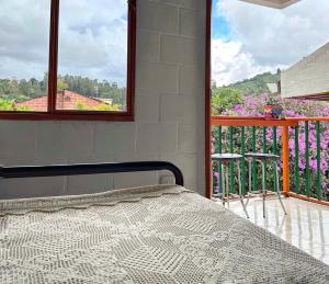a bedroom with a bed and a balcony with flowers at Casita entera en Salento para 10 personas cerca a la plaza in Salento