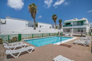 a swimming pool with lounge chairs and a house at Apartamento Princesa Teguise in Tías