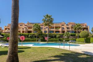 a resort with a swimming pool and a palm tree at Casares Beach luxe penthouse in Casares