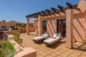 a patio with two couches and a pergola at Casares Beach luxe penthouse in Casares
