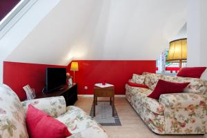 a living room with two couches and a red wall at Fewo Birkenallee - Rose in Deinste
