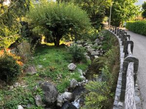 a stone fence next to a garden with rocks and trees at Appartement im Park in Minusio