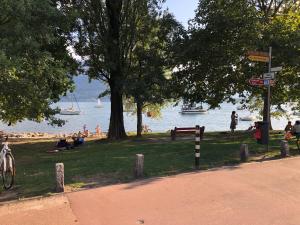 a park with people sitting on the grass near the water at Appartement im Park in Minusio