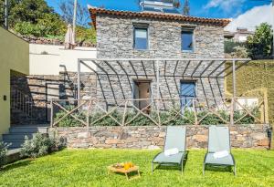two chairs and a table in front of a stone house at Ocean View Villas in Caniço