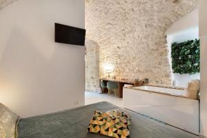 a bedroom with a stone wall with a bed and a desk at Eclissi suite in Giovinazzo